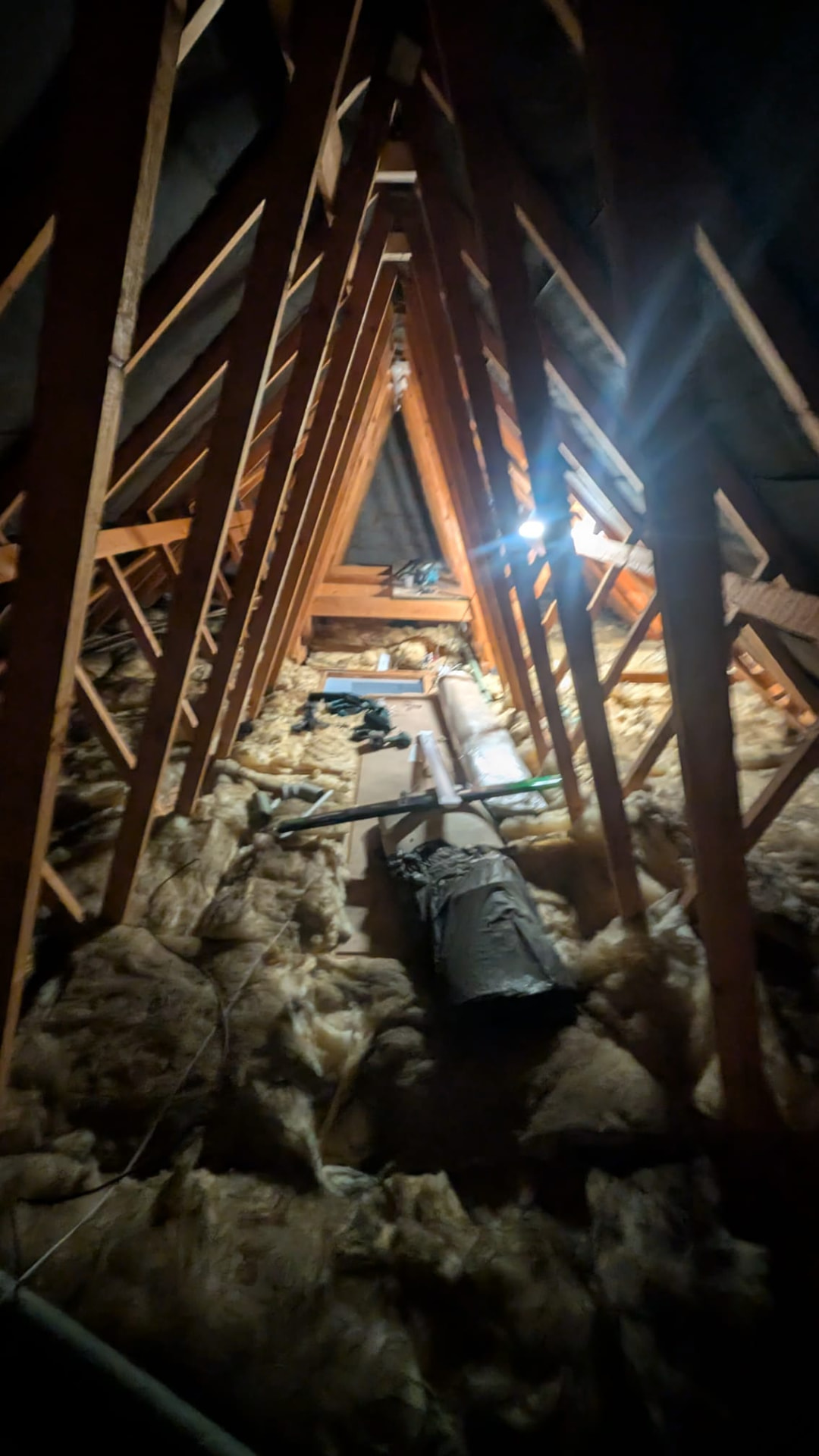 Loft before boarding, uneven mineral wool insulation between exposed joists with no usable floor