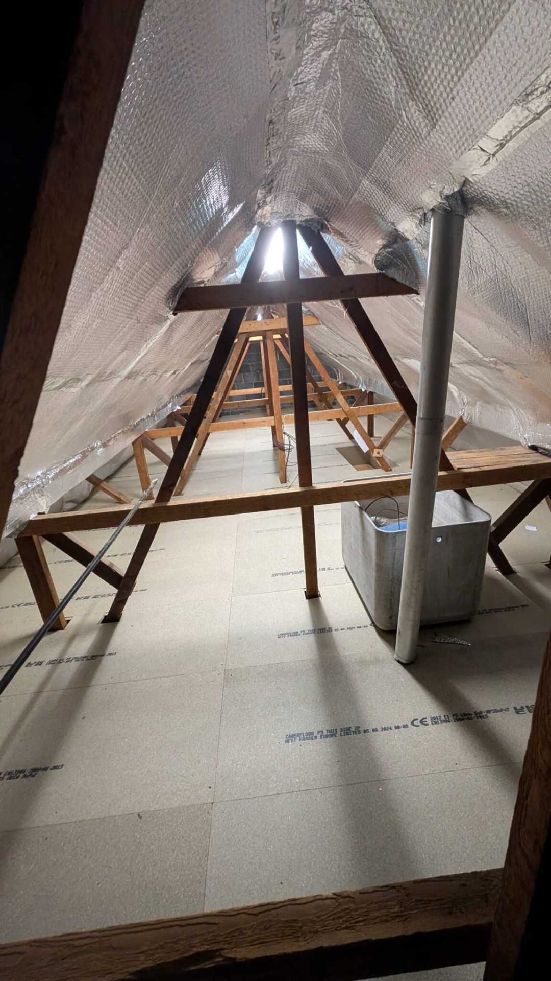 Foil loft lining around water tank with boarded floor below