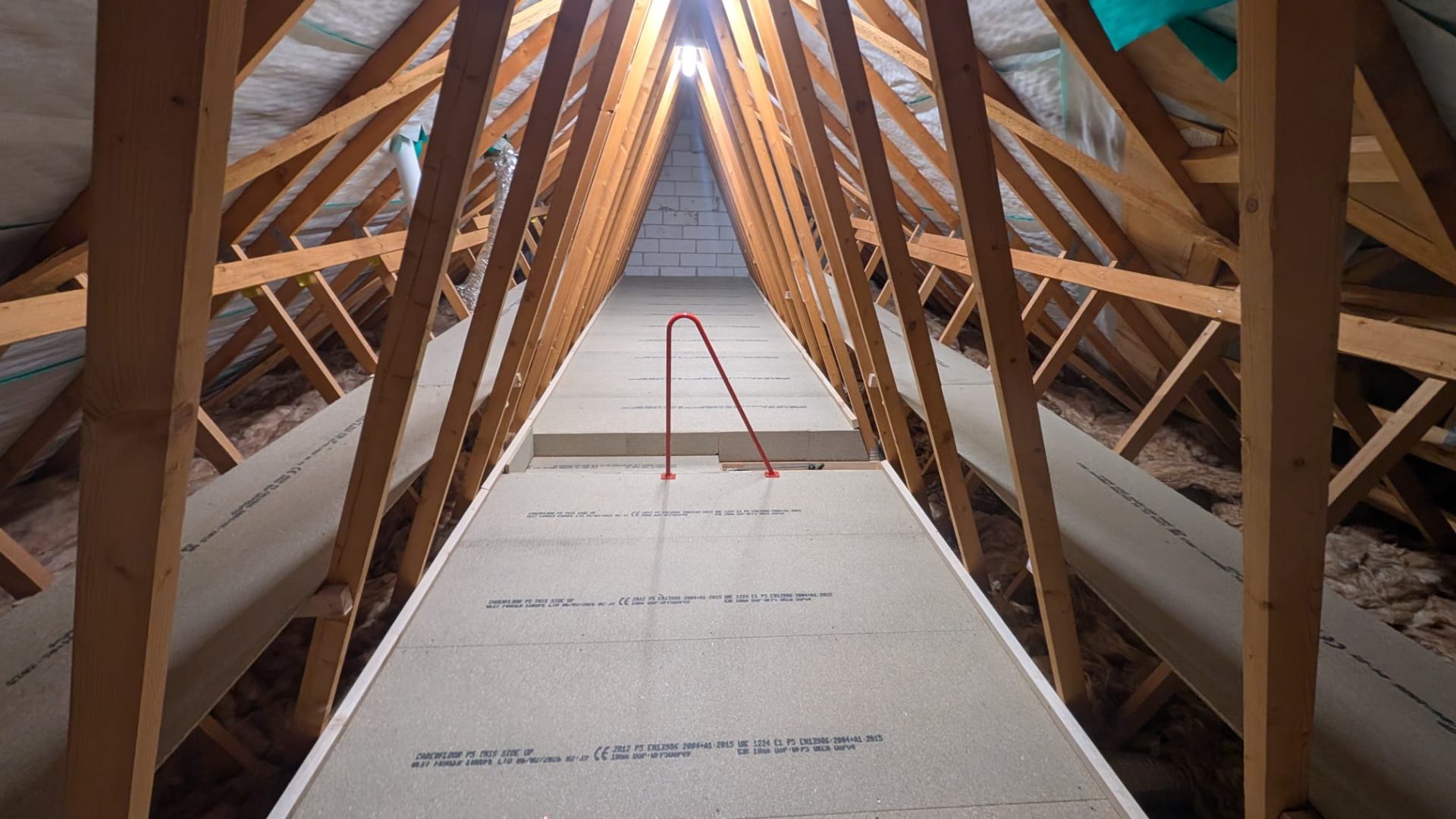 Loft boarding around vertical bracing in trussed roof